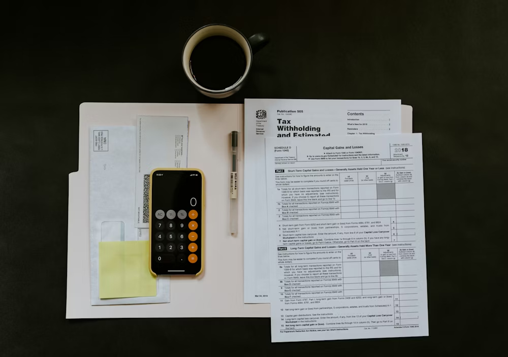 Tax forms, calculator, and coffee on a desk